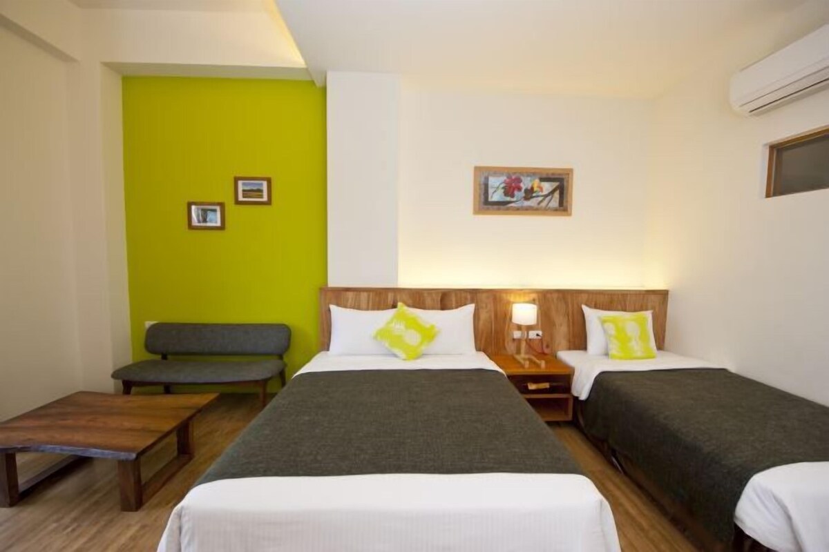 A hotel room with a bed, two bedside tables, a bench, and a small table.