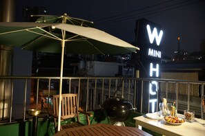 Eine Dachterrasse mit einem grünen Sonnenschirm, einem Grill und einem Schild mit der Aufschrift 'W MINI H'.