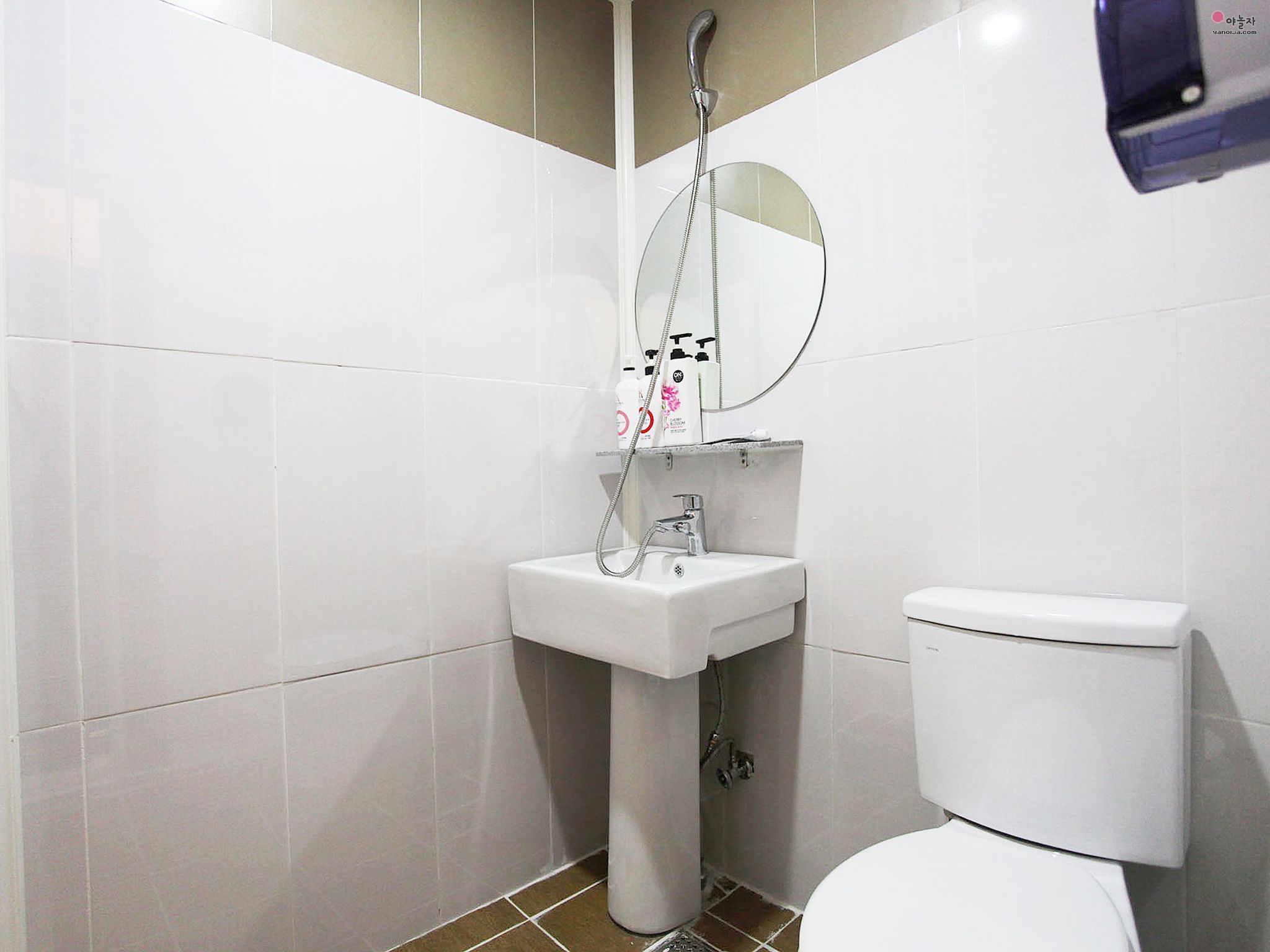 Un baño con lavamanos blanco, espejo y retrete.
