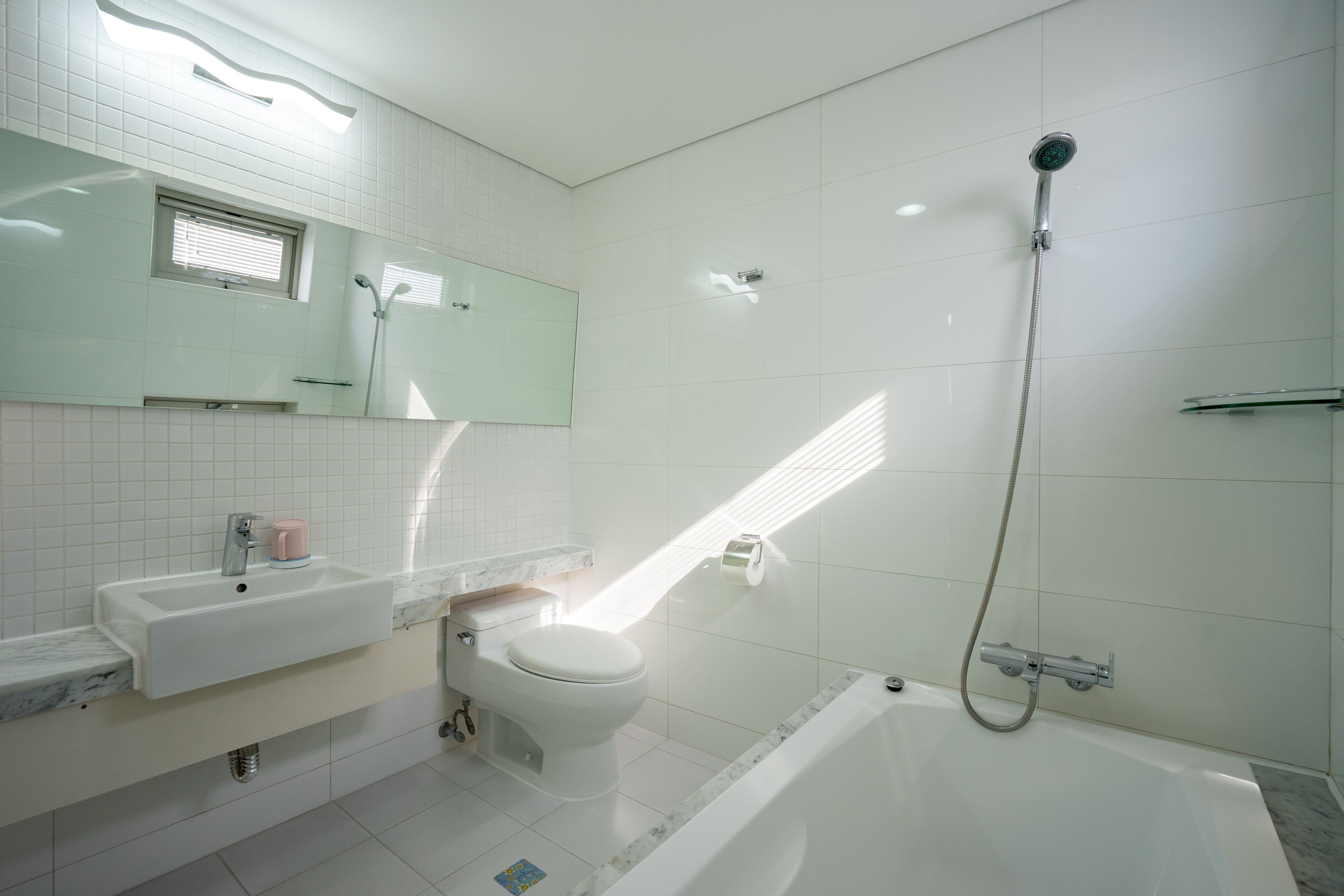 Uma casa de banho moderna com uma pia, sanita e banheira brancas.