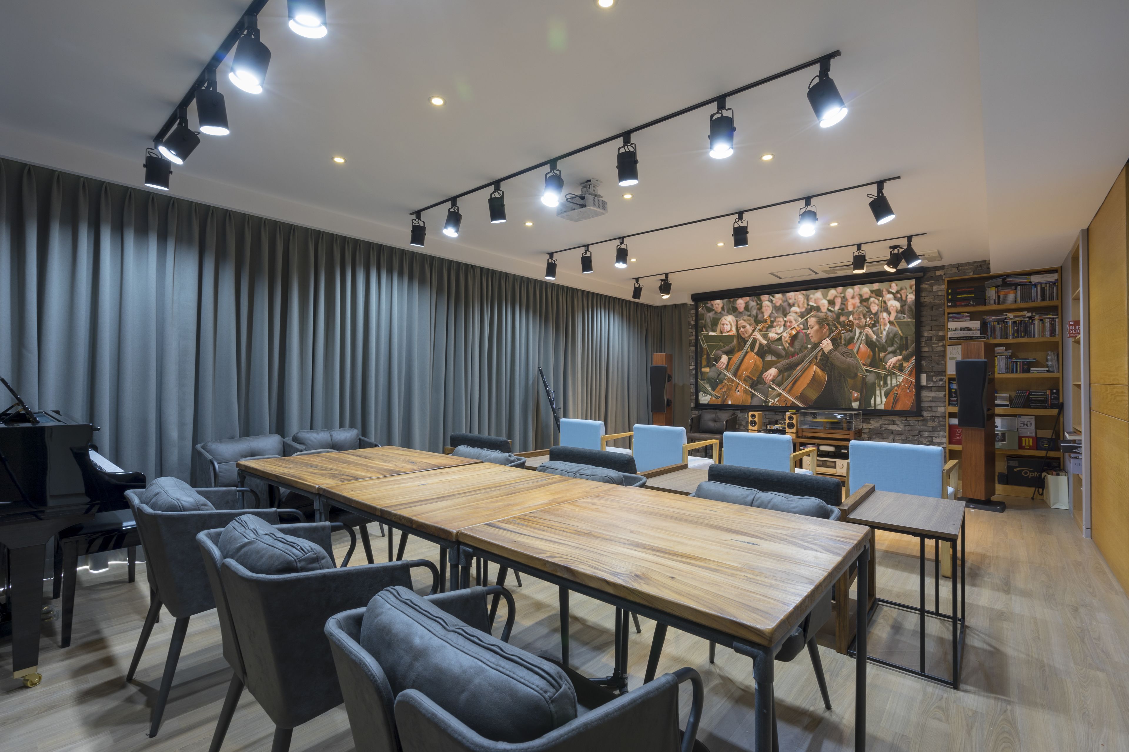 Un salón de conferencias con una larga mesa, sillas, un piano y un mural grande.
