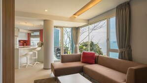 A modern living room with a sofa, a coffee table, and a view of the outdoors through large windows. - Tacet Pension (Tongyeong)