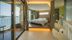 A modern hotel room with a balcony, a bed, a bathroom, and a dining area. - Tacet Pension (Tongyeong)
