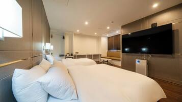 Una habitación de hotel moderna con una cama grande, un televisor de pantalla plana y aire acondicionado integrado.