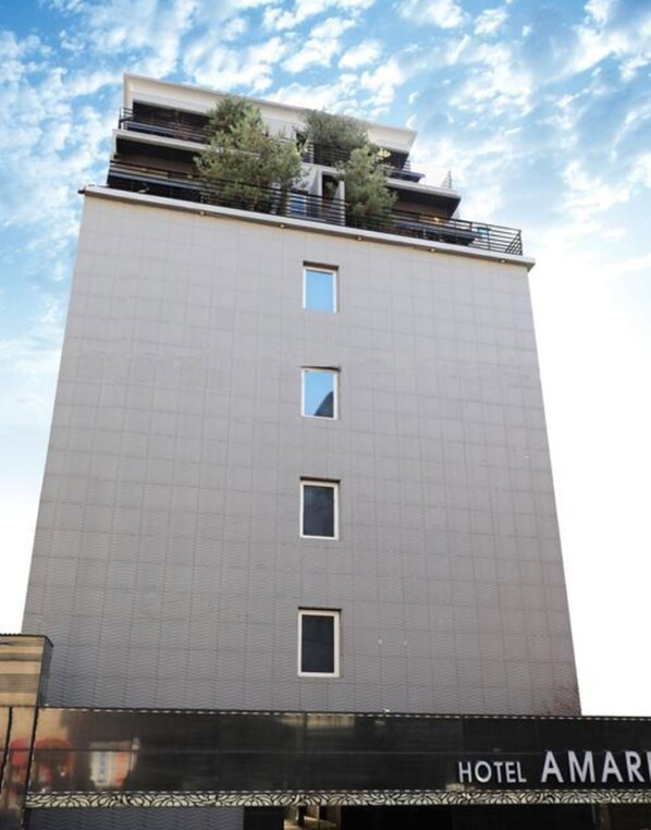 A modern hotel building with a flat facade, multiple windows, and a rooftop garden.