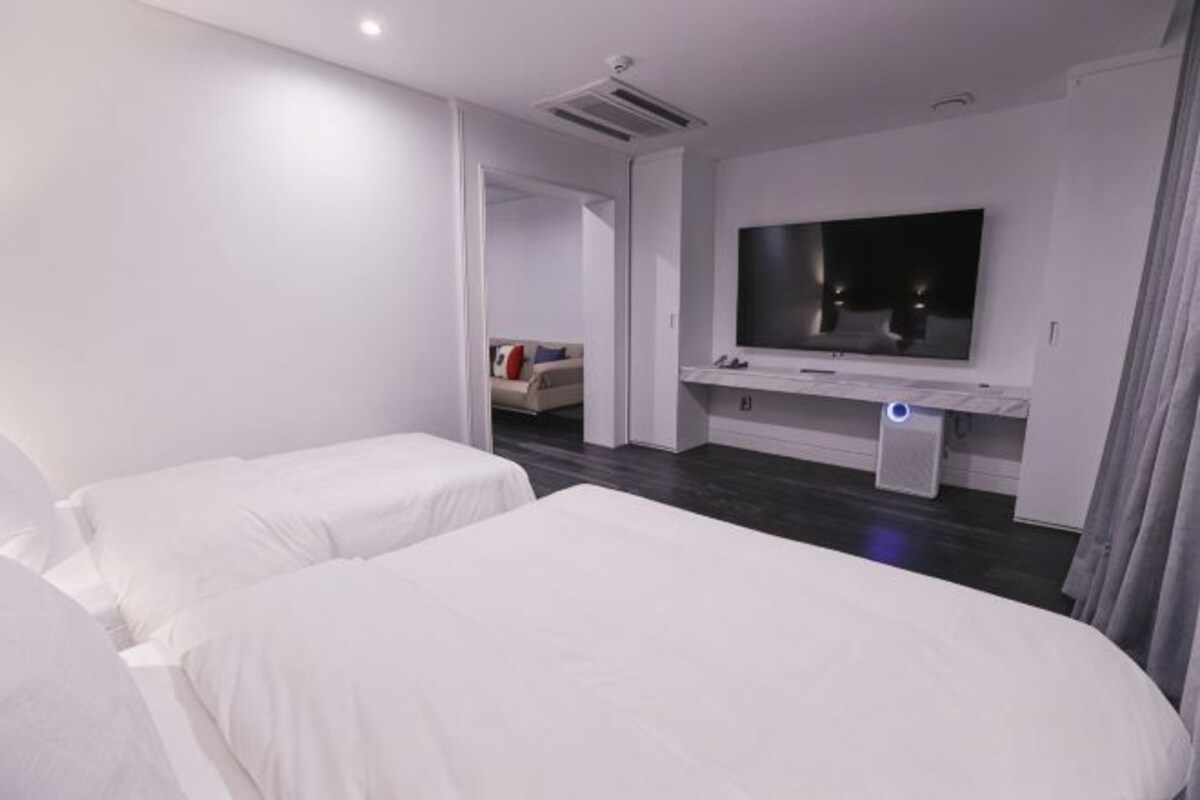 A hotel room with two beds, a TV, and a bedside table.