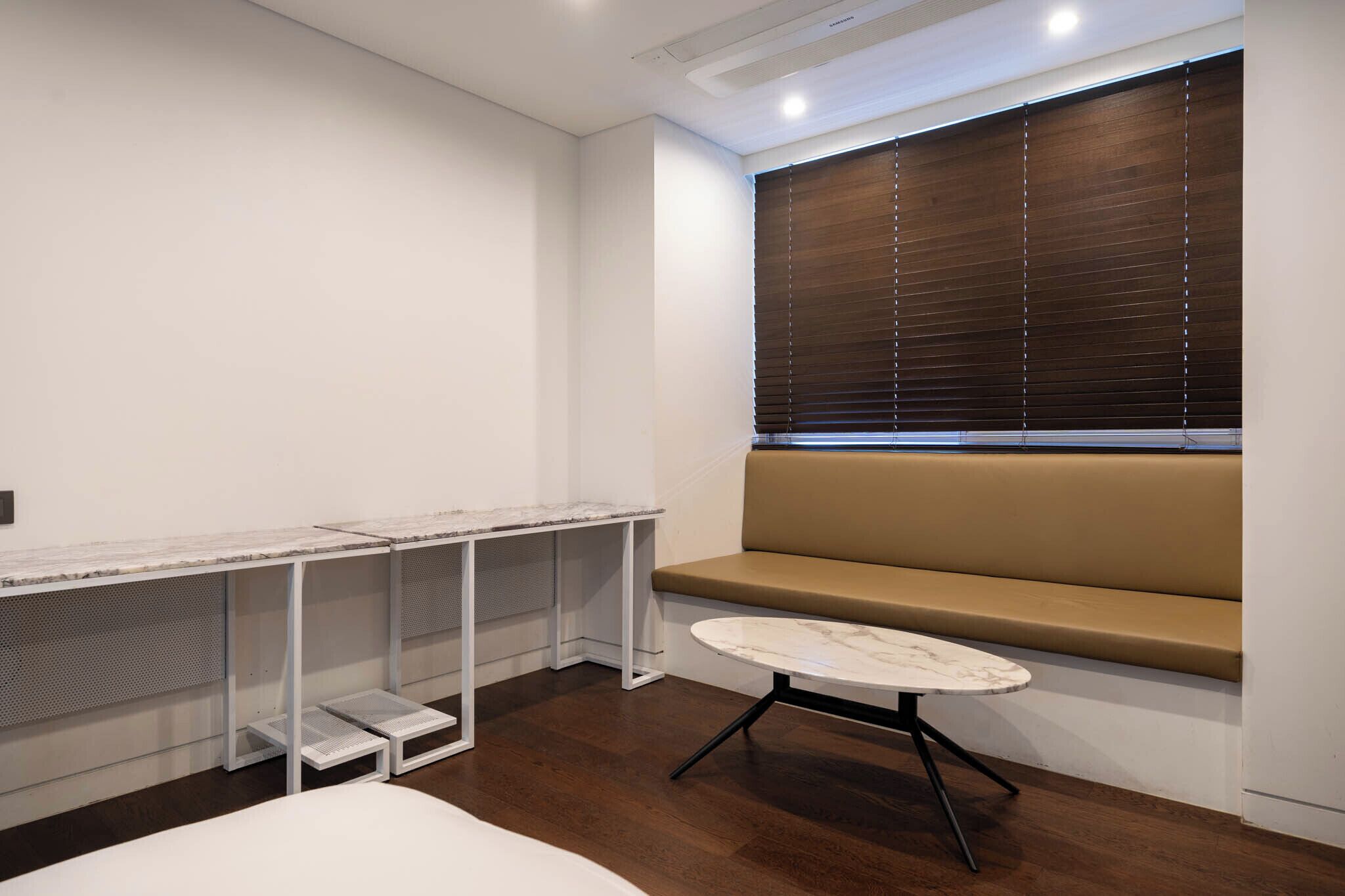 A modern room with a bench, a small table, and a window with blinds.