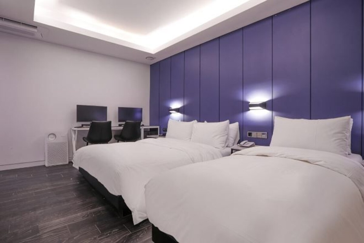 A hotel room with two beds, a desk with a computer, and a TV.