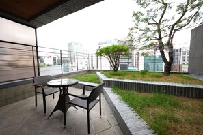 A balcony with a table and chairs, a tree, and a view of city buildings.