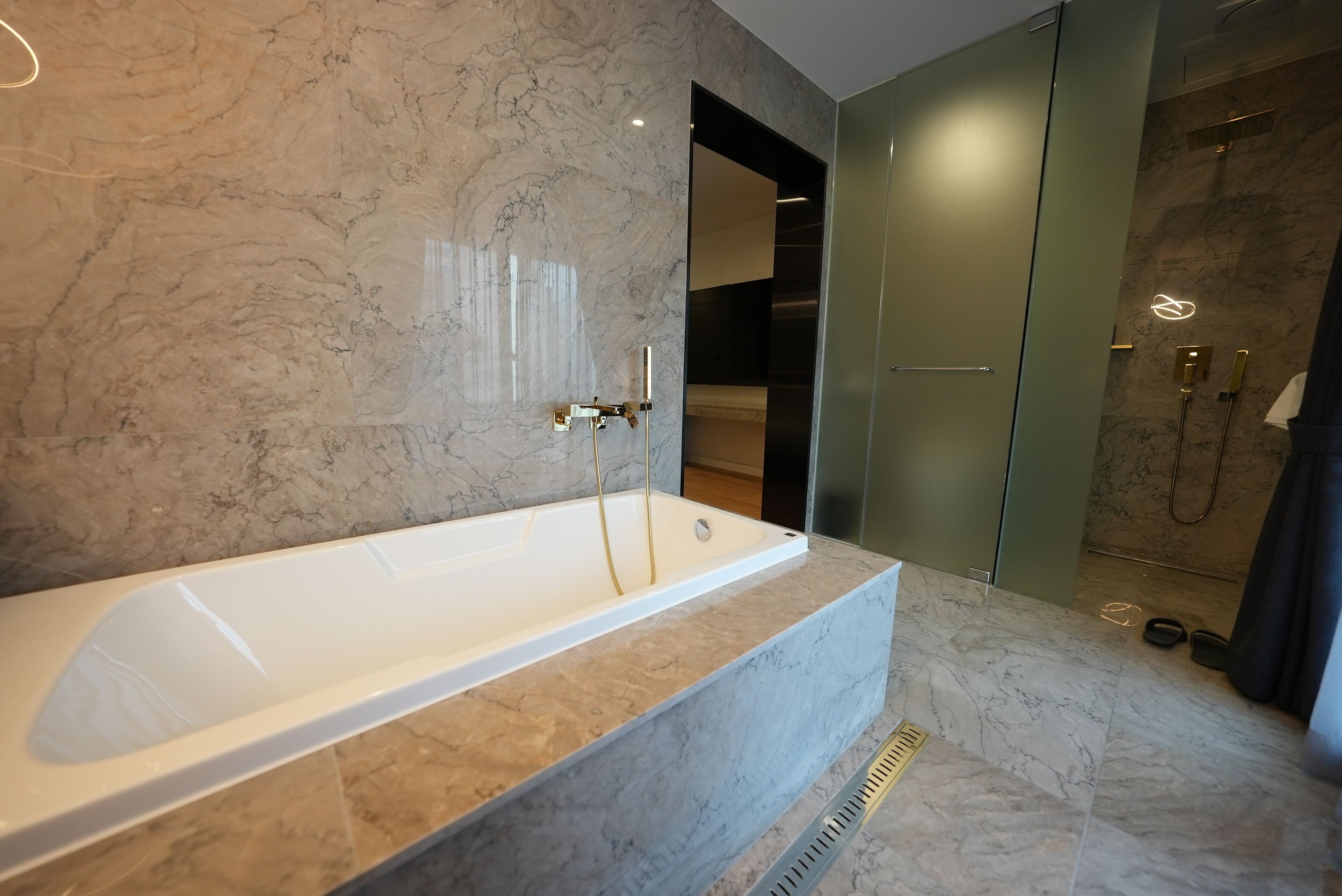 A modern bathroom with a marble sink, a bathtub, and a glass shower enclosure.