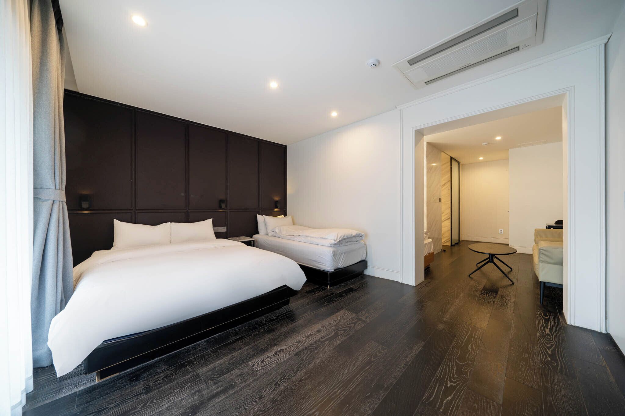 A modern hotel room with a large bed, a smaller bed, a desk, and a chair.