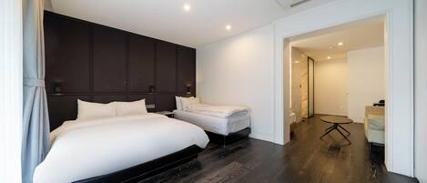 A modern hotel room with a large bed, a smaller bed, a desk, and a chair.