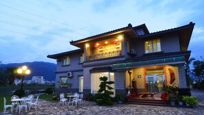 A two-story house with a balcony, stone patio, and outdoor seating area. - Yunju Hotspring Villa (Jiaoxi)