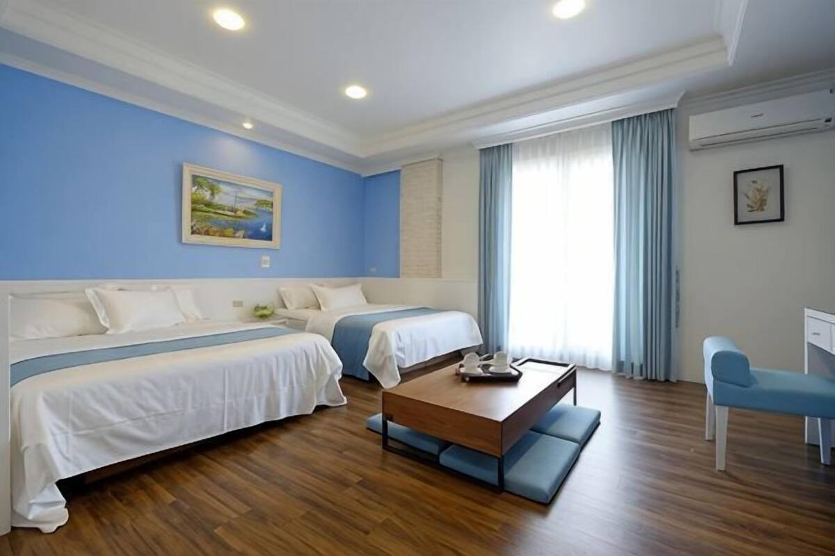 Une chambre d’hôtel avec deux lits, une table basse en bois, un bureau et une chaise.