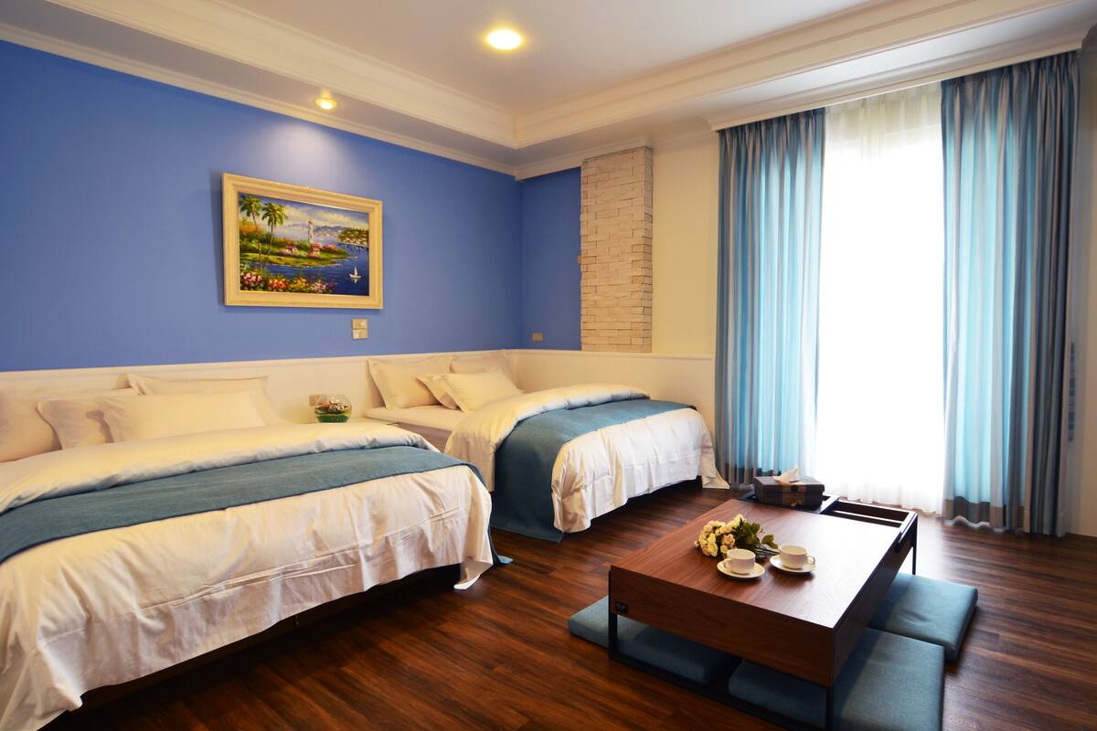 Une chambre d’hôtel avec deux lits, une table basse en bois et un tableau au mur.