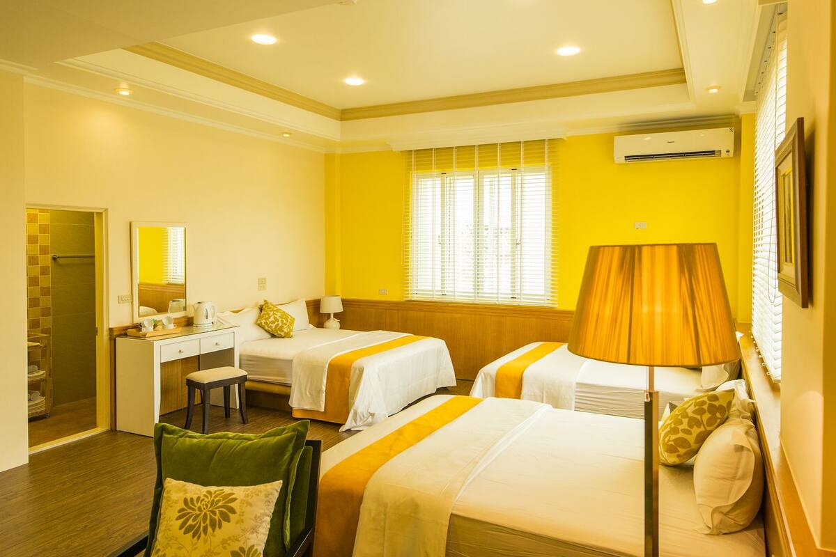 Une chambre d’hôtel avec deux lits, un bureau, une chaise et une lampe.