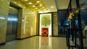 A lobby with a marble floor, an elevator, a reception desk, and a decorative tree sculpture. - Diamond City Place (Pattaya)