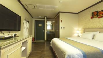 Une chambre d’hôtel avec un lit, une télévision, un bureau avec un ordinateur et une salle de bain visible à travers une porte ouverte.