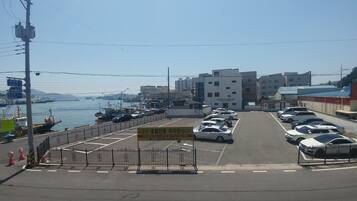 A parking lot with cars, a coffee factory building, and a view of the sea with boats.