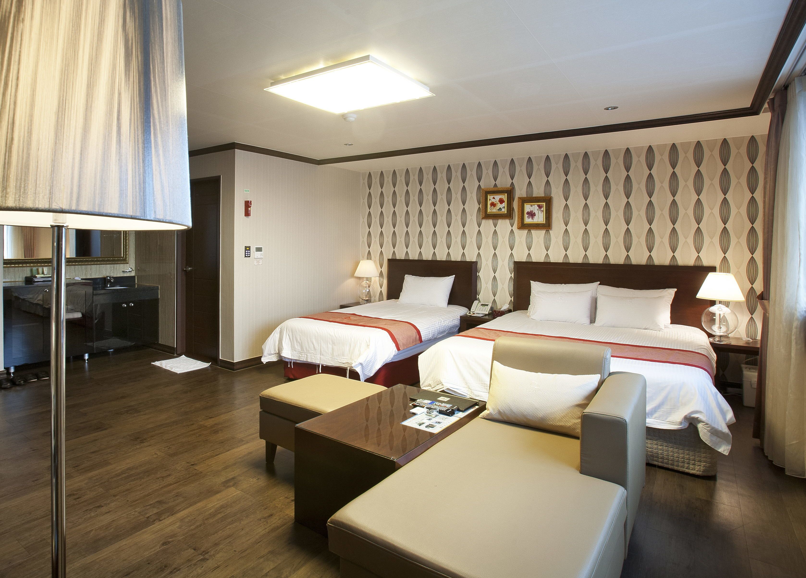 Una camera d'albergo con due letti, una scrivania, una sedia e un piccolo tavolino.