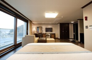 A hotel room with a large bed, a desk, a chair, and a view of the outside. - Tongyeong Anchovy tourist Hotel (Tongyeong)