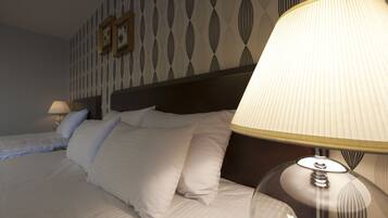 A hotel room with two beds, a headboard, and a lamp.