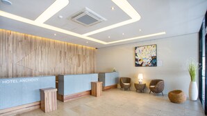 A hotel reception area with a modern design, featuring a reception desk, seating area, and artwork on the wall. - Tongyeong Anchovy tourist Hotel (Tongyeong)