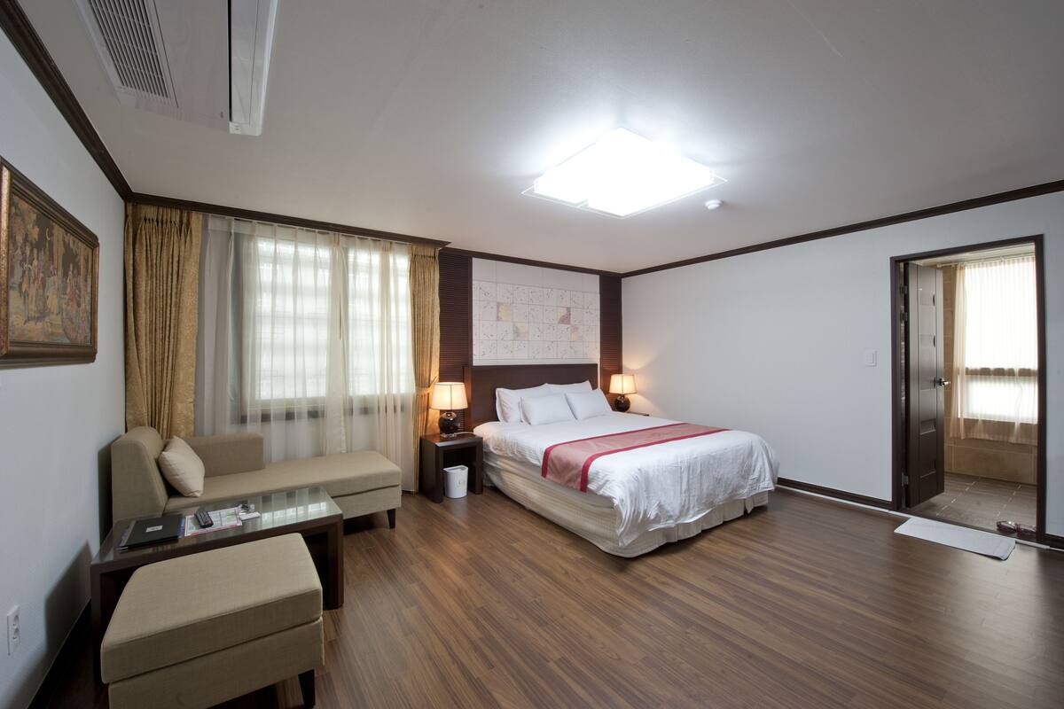 A hotel room with a bed, a sofa, a desk, and a nightstand.