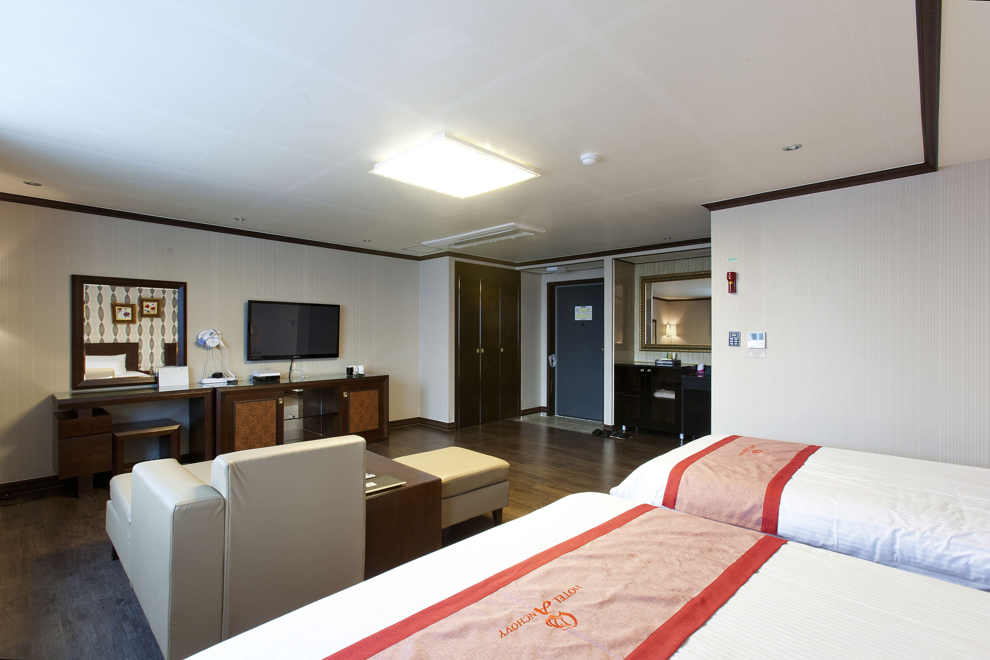 A hotel room with a bed, a desk, a chair, a television, and a mirror.