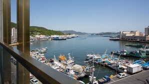 A marina with boats docked, a clear sky, and a hilly landscape in the background. - Tongyeong Anchovy tourist Hotel (Tongyeong)