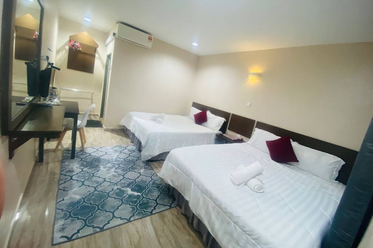 Une chambre d’hôtel avec deux lits, un bureau, une chaise, un miroir et un tapis à motifs.