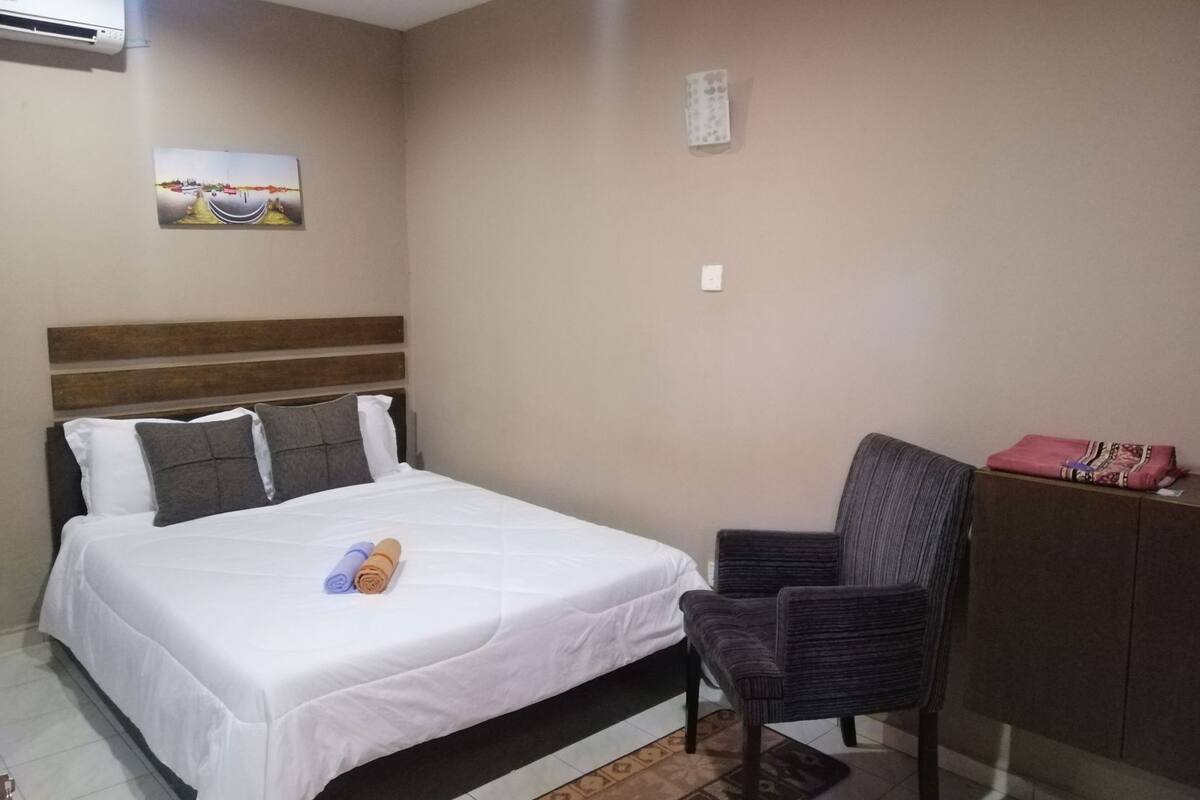 Une chambre d’hôtel équipée d’un lit, d’une chaise, d’un bureau et d’un climatiseur fixé au mur.