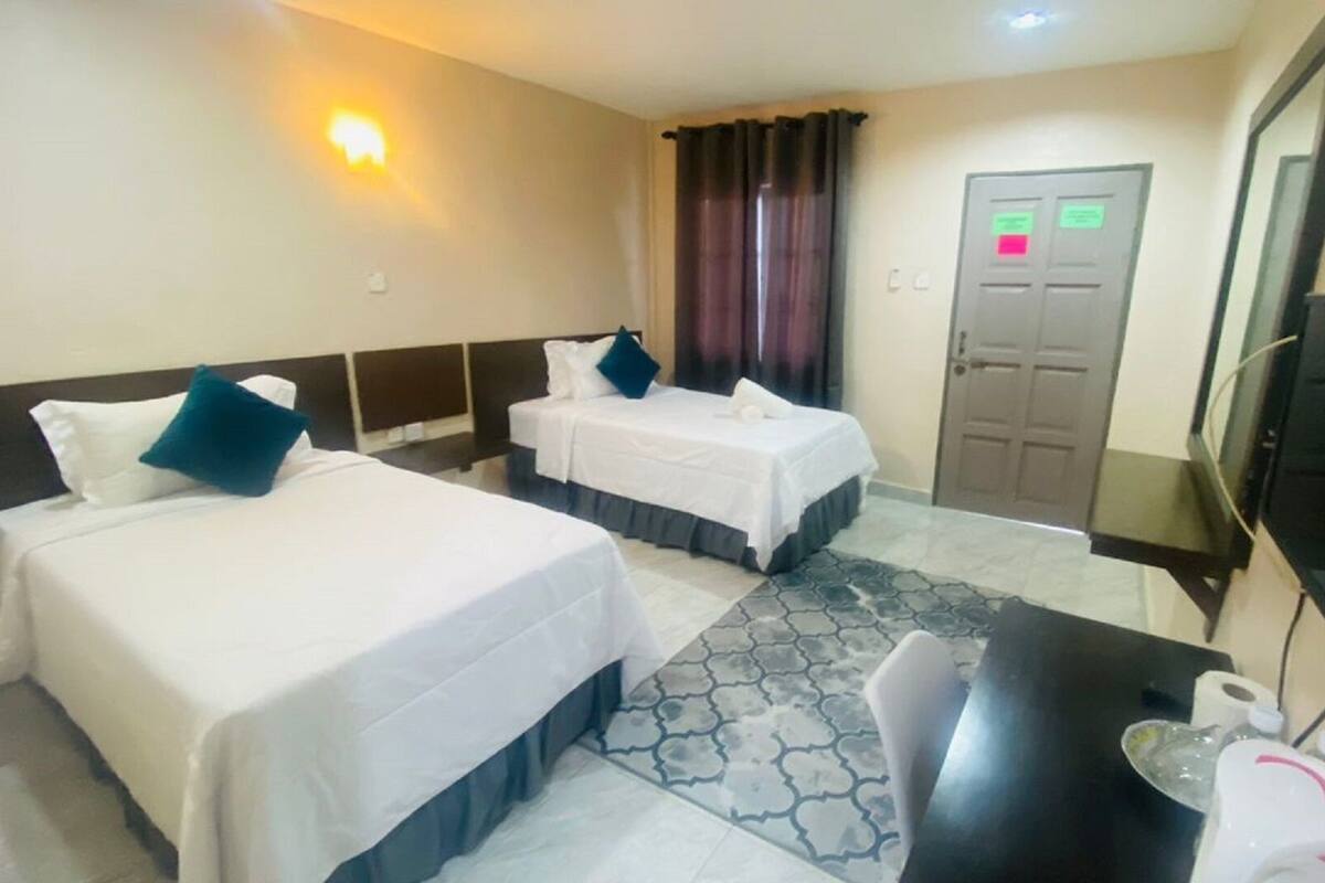 Une chambre d’hôtel avec deux lits, un bureau, une chaise, une télévision et une porte dotée d’un panneau de sécurité.