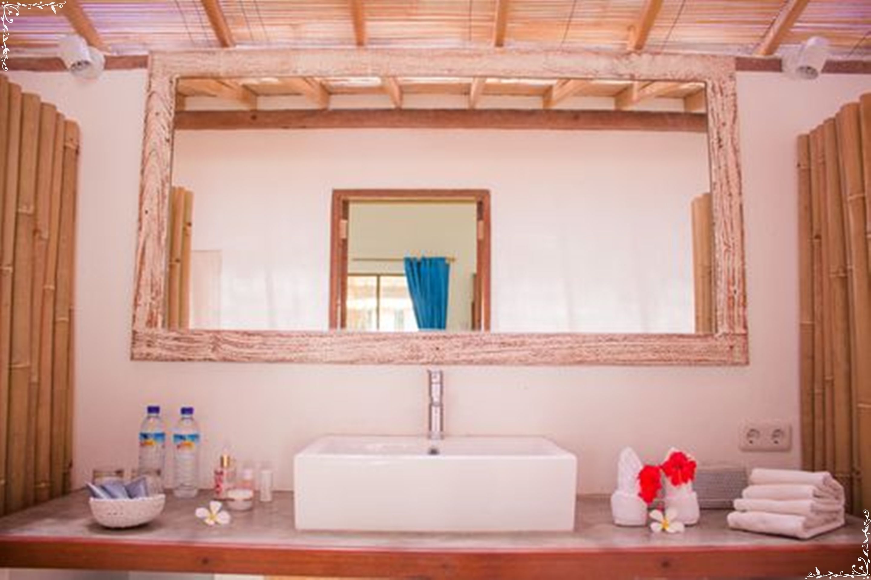 A bathroom with a large mirror, a rectangular sink, and a wooden ceiling.