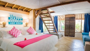 Une chambre à coucher avec un lit, un escalier, une chaise bleue et une grande fenêtre.