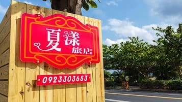 A wooden sign with a red and yellow border, Chinese characters, and a phone number.