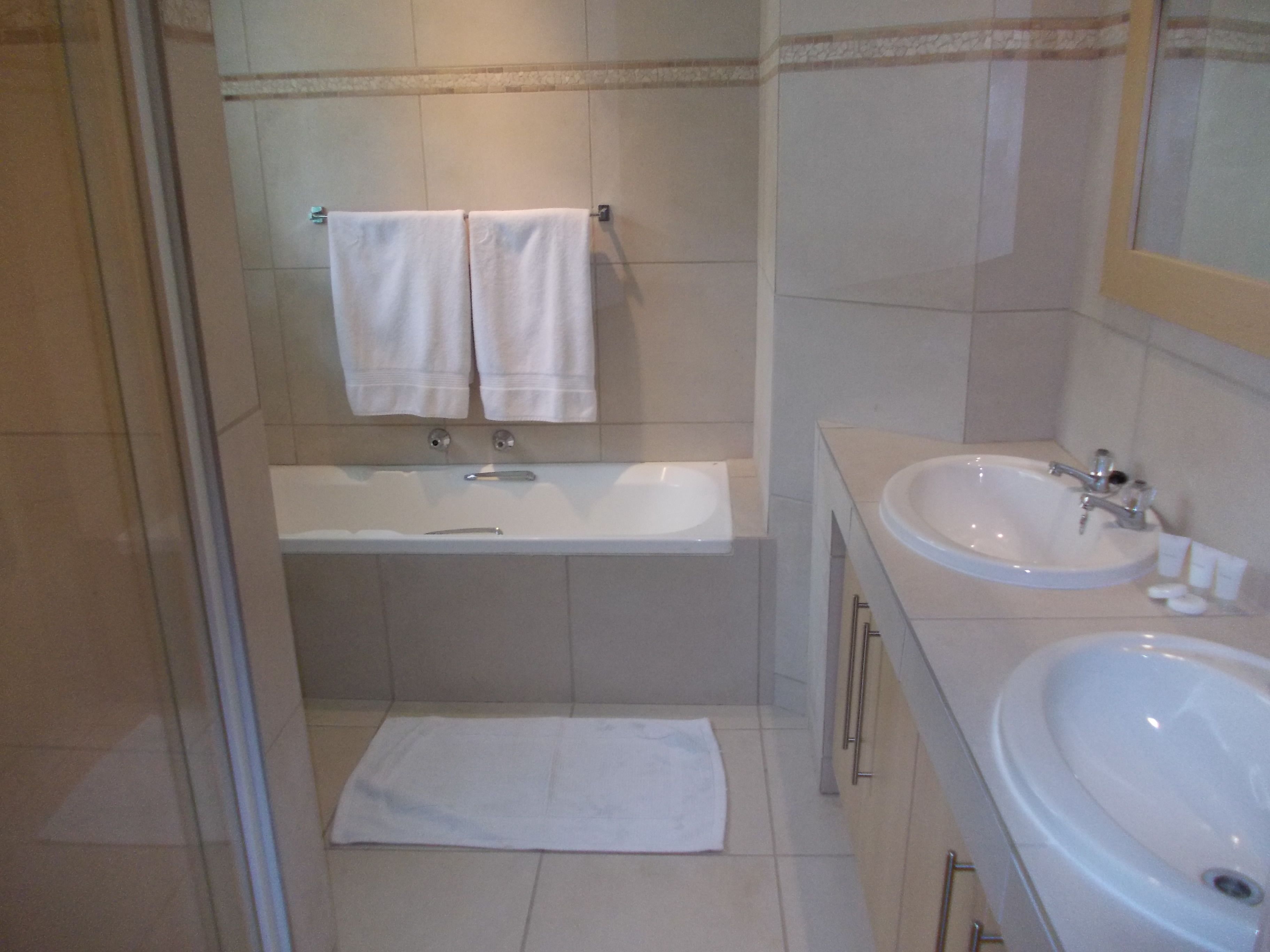 A bathroom with a bathtub, a sink, and two towels hanging on the wall.