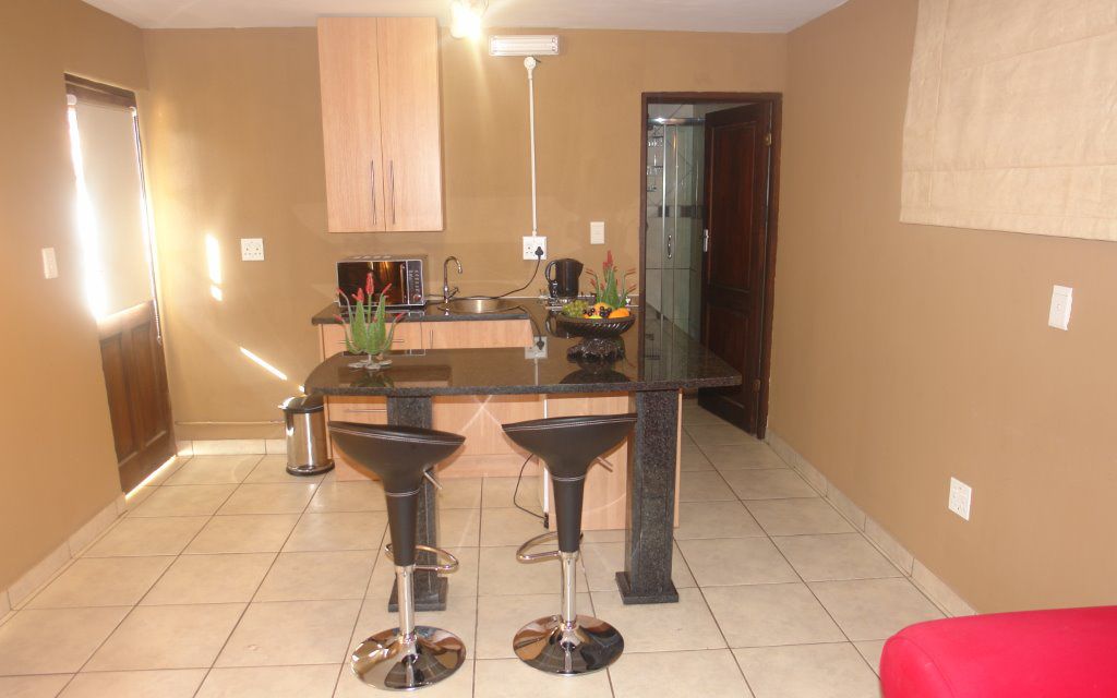 A modern kitchen with a central island, two bar stools, and a red couch.