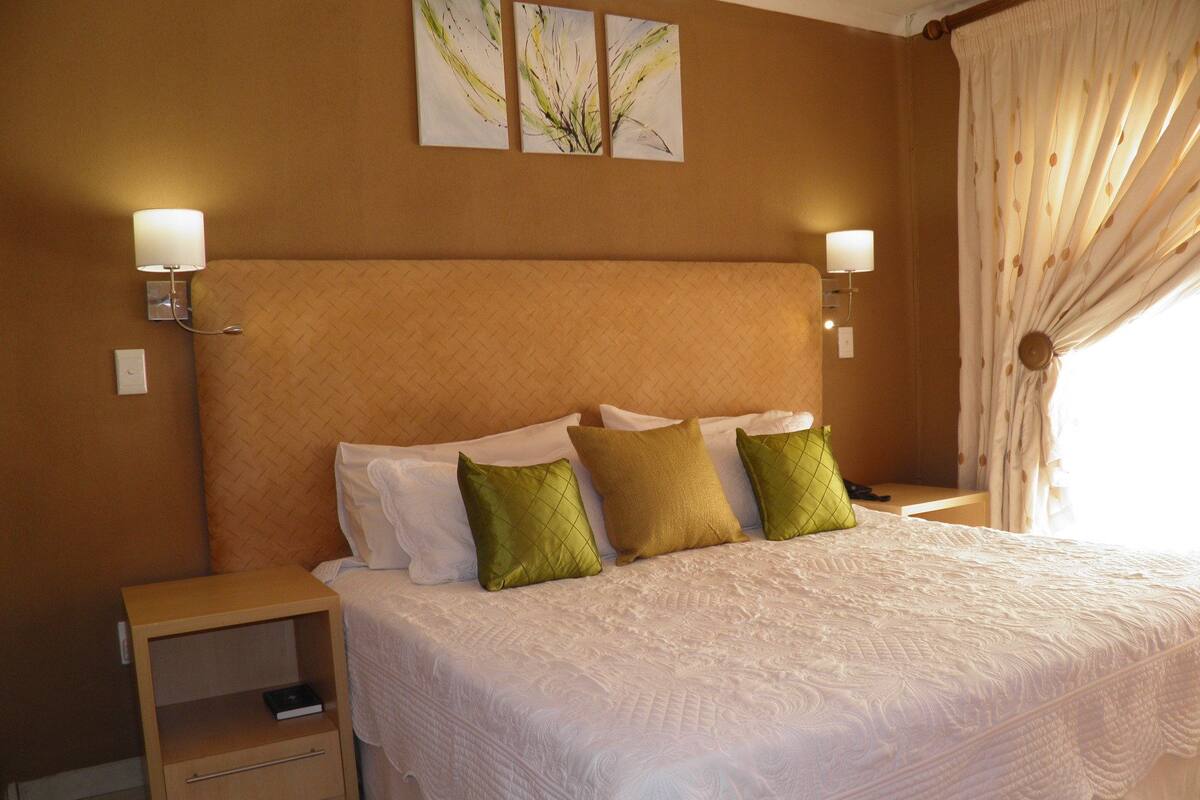 A hotel room with a large bed, two bedside lamps, a nightstand, and a wall-mounted artwork.