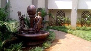 A garden with a fountain, a pathway, and a building with lattice windows.