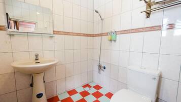 A bathroom with a white sink, toilet, and shower. The floor has a red and white checkered pattern.
