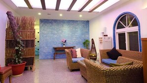 Un salon chaleureux avec des meubles en osier, un mur bleu à la texture intéressante et un plafond en bois.