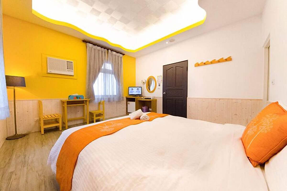 A hotel room with a bed, a desk, a chair, a television, and a door.