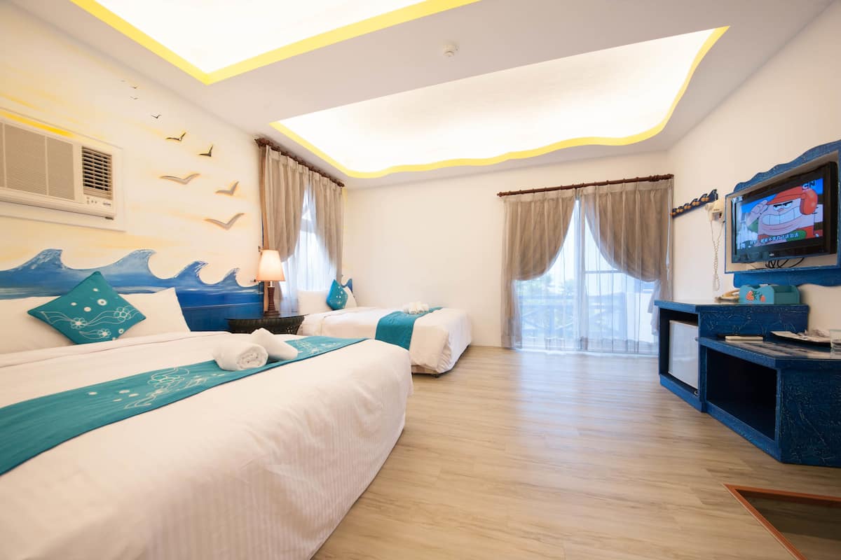 A hotel room with two beds, a TV, and a desk.