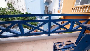 Un balcon avec une balustrade bleue, une petite table et une chaise.
