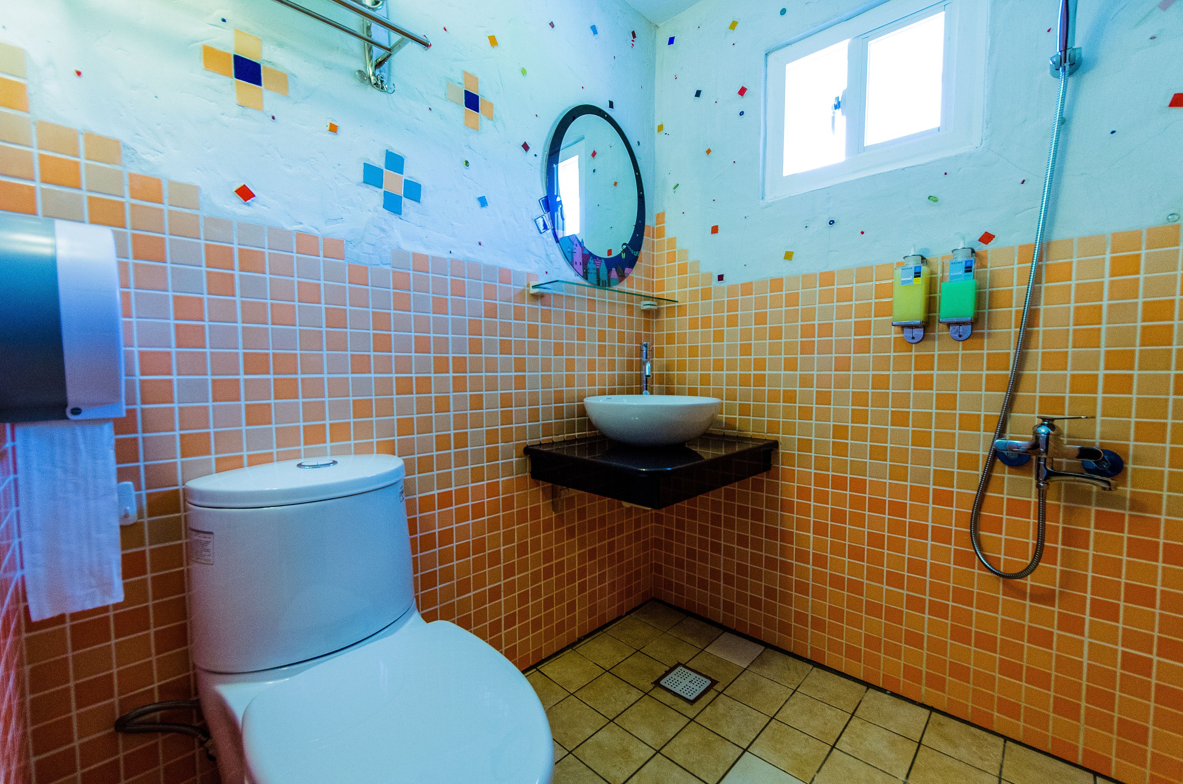 A bathroom with a toilet, a sink with a mirror, and a shower.