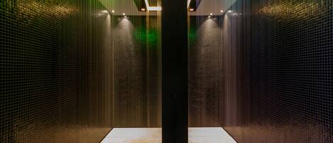 A modern elevator with a metallic finish and green lighting accents.