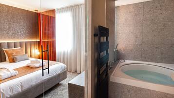 A modern hotel room with a large bed, a separate bathroom with a bathtub, and a view of the city.