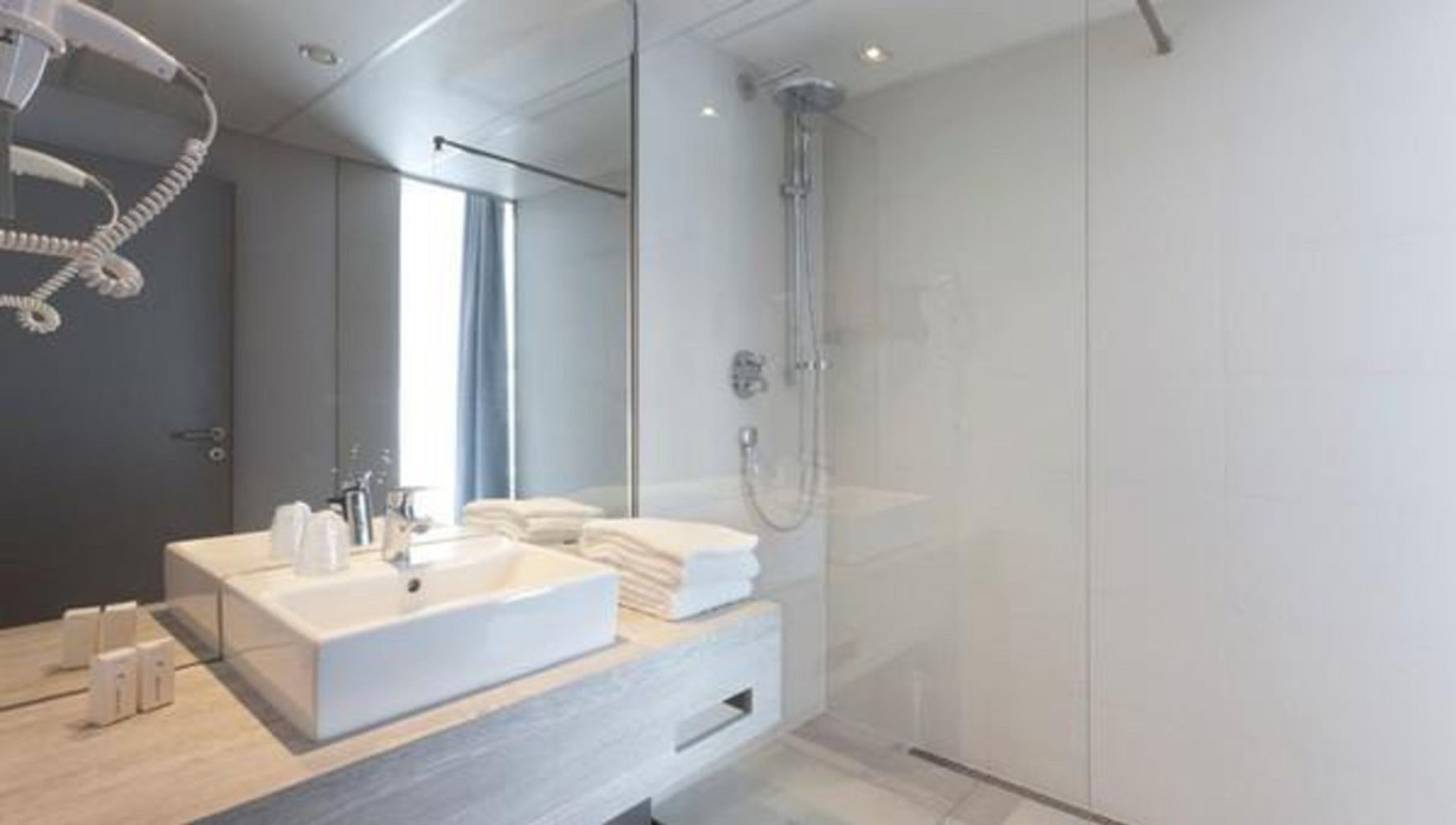 A modern bathroom with a large mirror, a dual sink vanity, and a glass-enclosed shower.