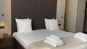 A modern hotel room with a large bed, two bedside tables, a bedside phone, and a mirror.